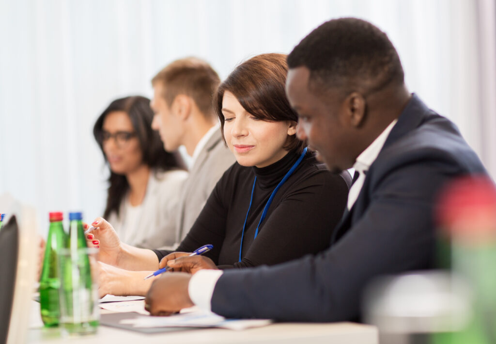 business, people and education concept - businessman and businesswoman at conference discussing papers