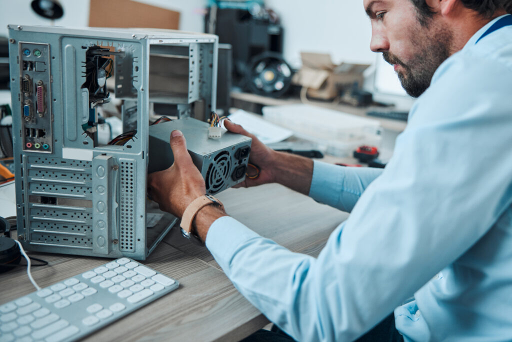 Engineering, technician and man fixing the hardware of a computer in workshop or office. IT, techno.