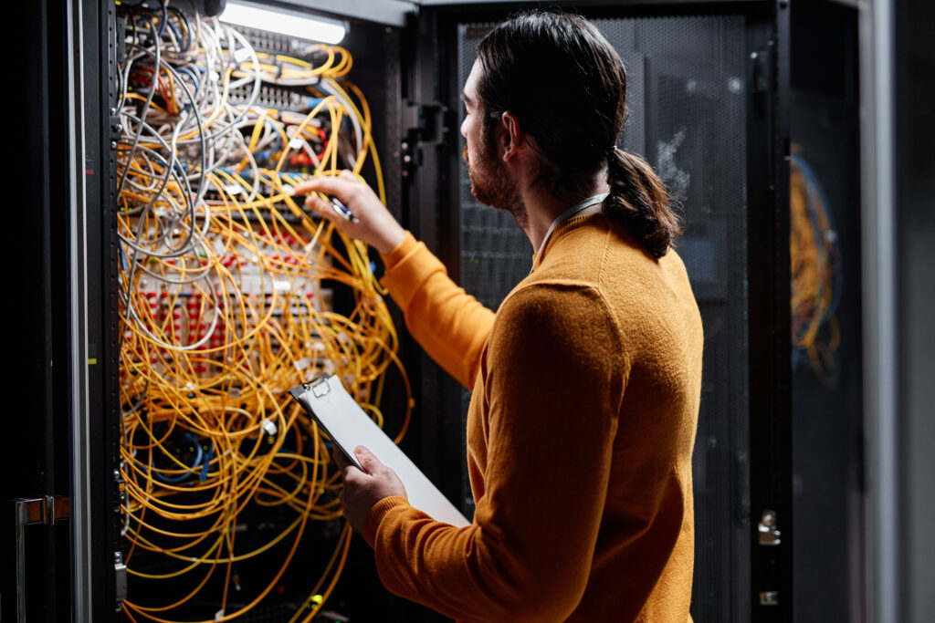 Side view portrait of network technician working with servers and connecting cables