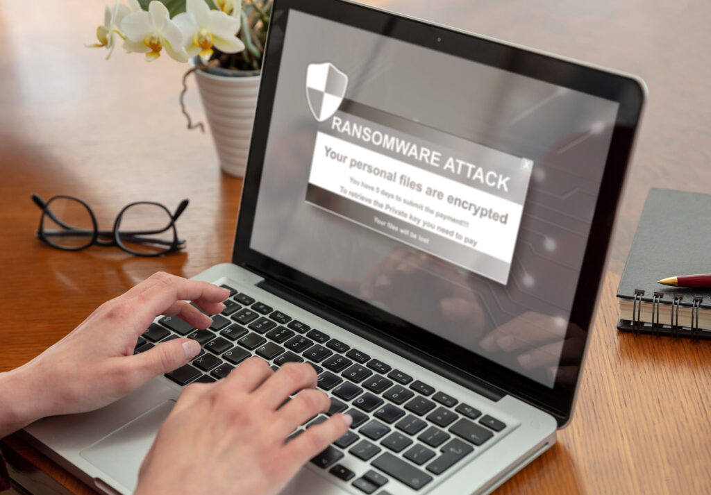 Ransom ware, Cyber attack concept. Warning message on a computer screen. Woman working with a laptop. Office business wood table background.